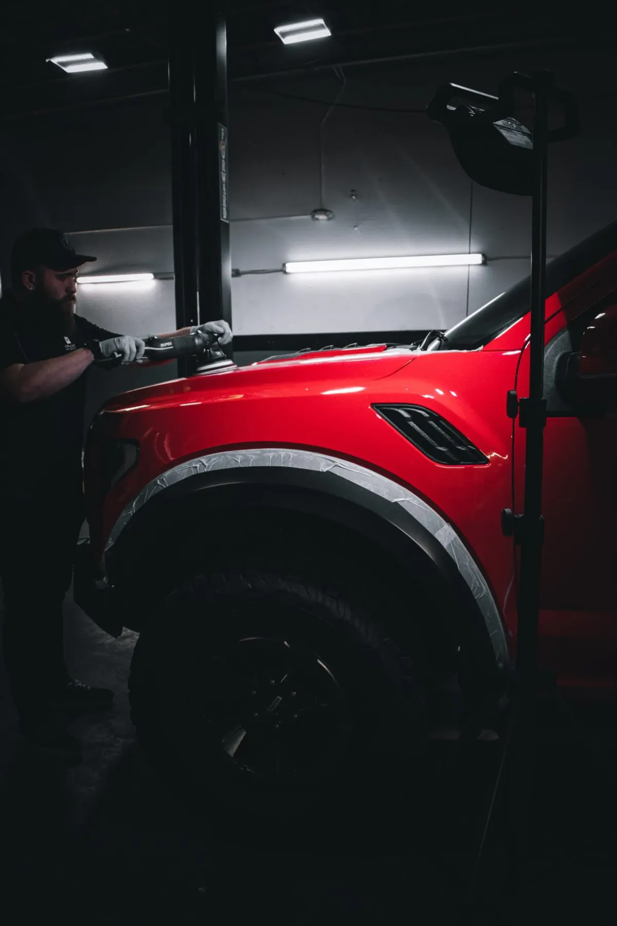 Technician polishing the paint on a red vehicle